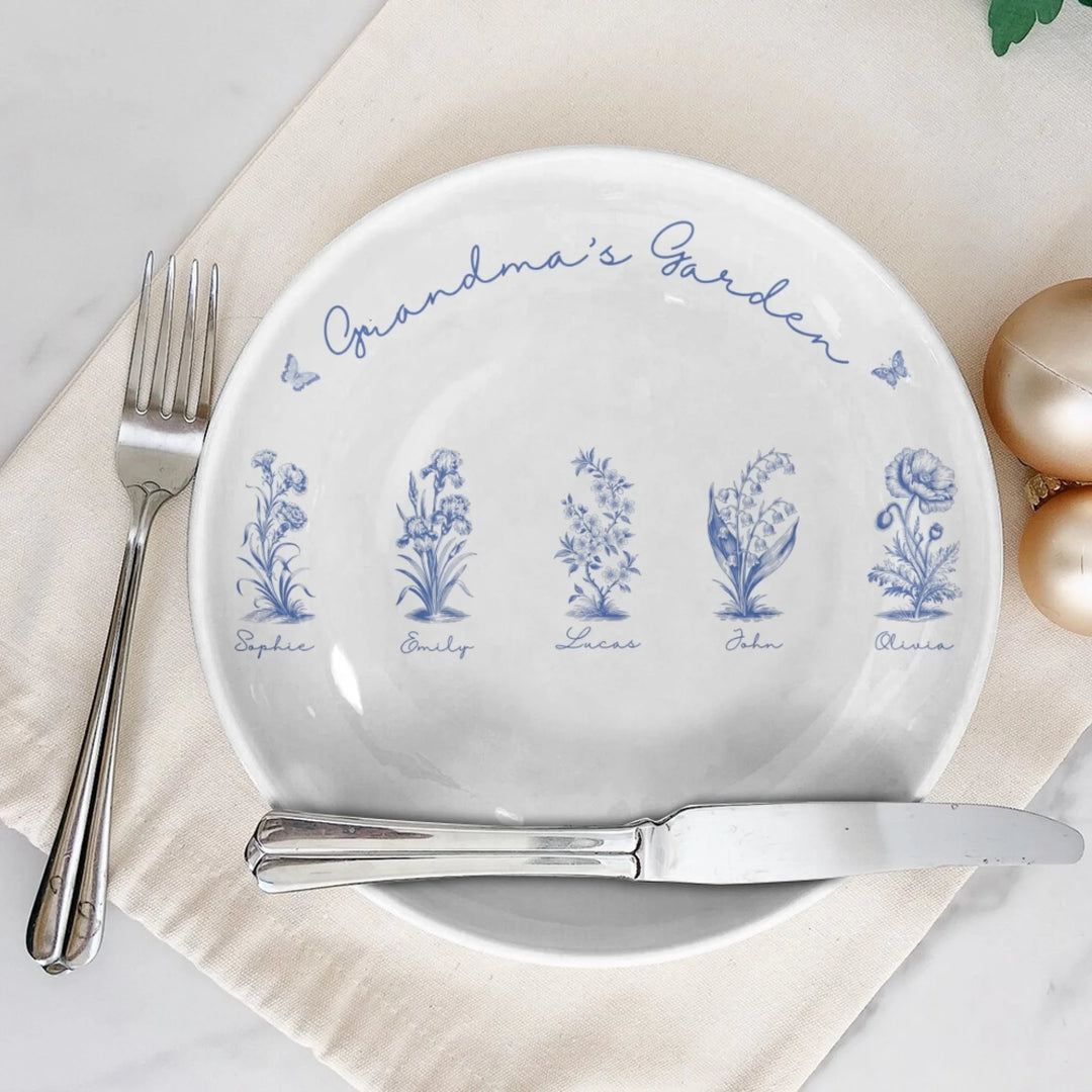 Custom toile birth flower ceramic plate with personalized title, names, butterflies, and floral motifs in blue, on table-ARTFULANE