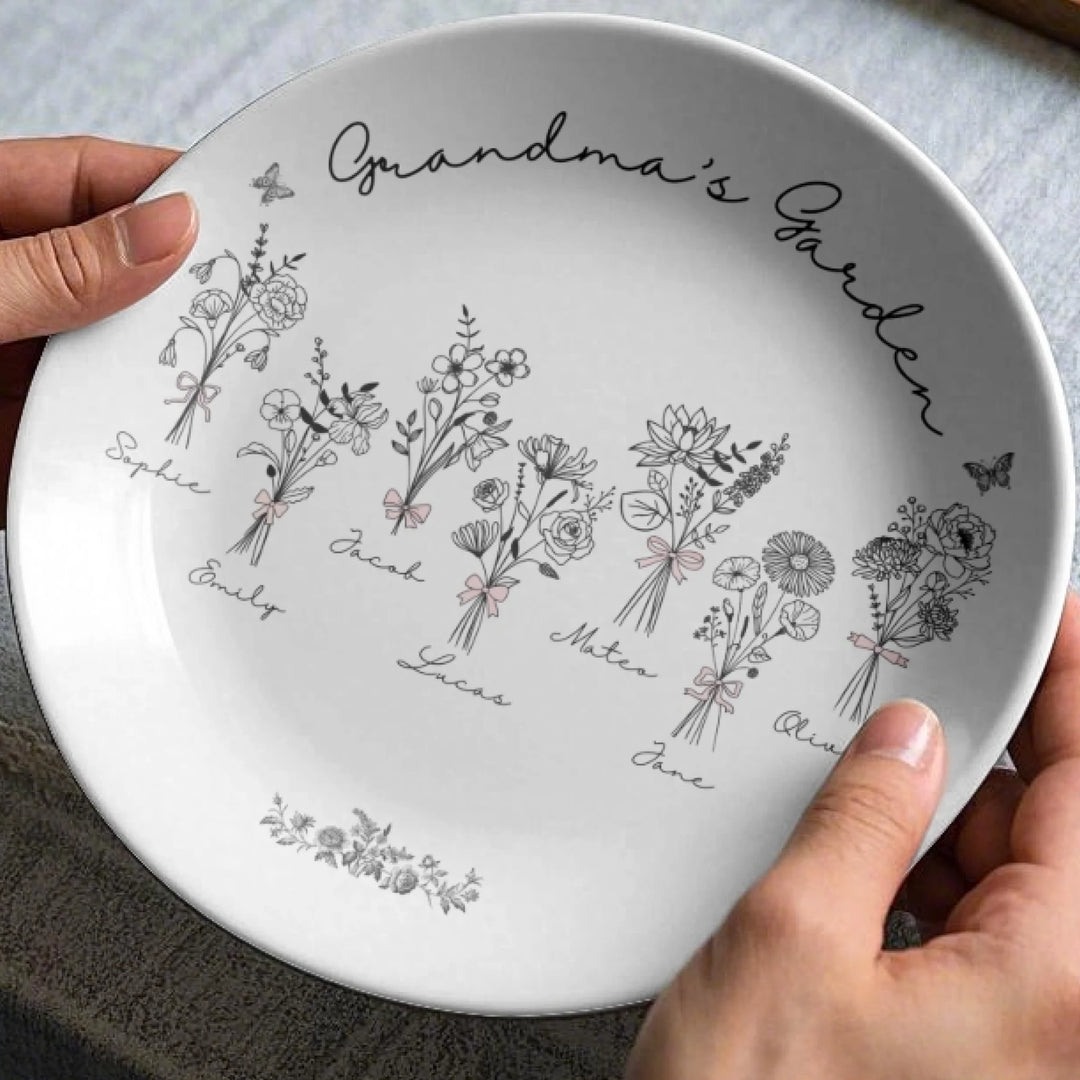 In hands - Custom coquette birth flowers ceramic plate with stand featuring 12 delicate floral designs, personalized names, and custom title in any color by ARTFULANE