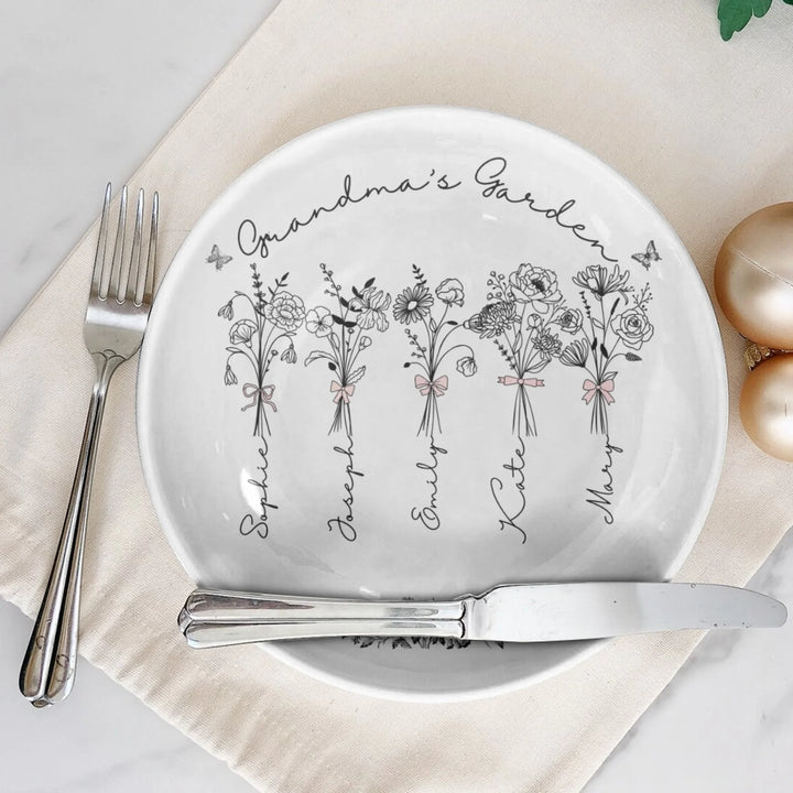 On table - Custom Coquette birth month flowers ceramic plate with stand featuring delicate floral line art, custom family names, and optional butterflies, available in any color by ARTFULANE